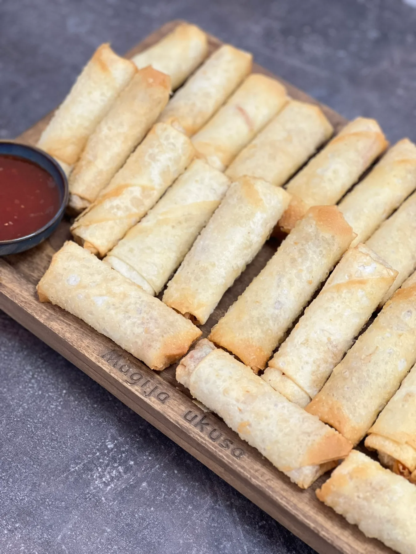 Veganske prolećne rolnice servirane na drvenoj dasci uz slatko kiseli čili umak